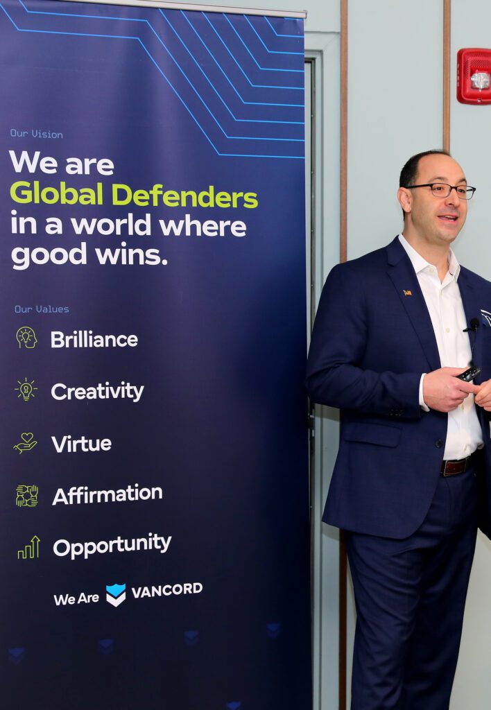 Michael Grande standing near a poster that presents our company’s vision and values.